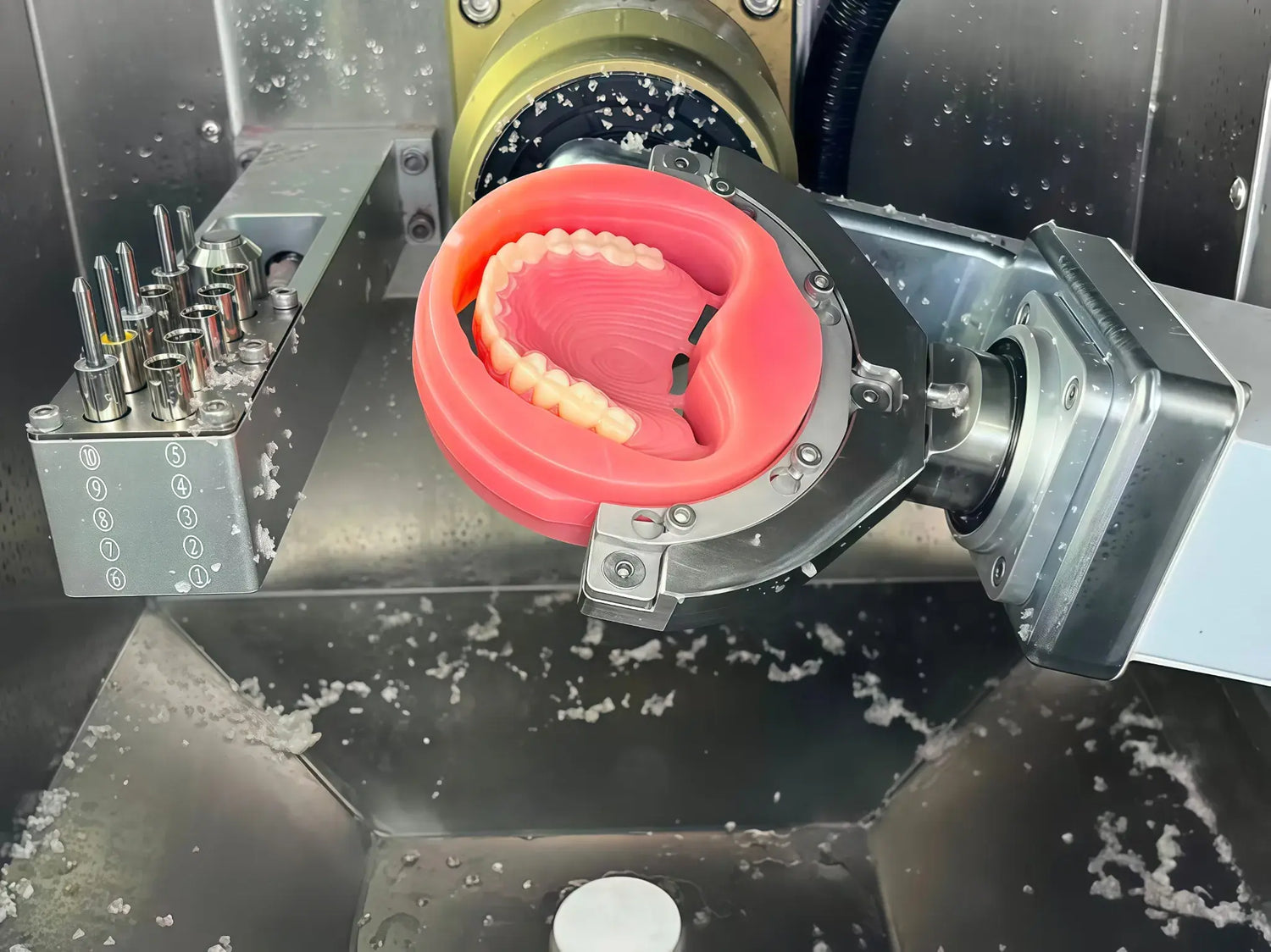 Pink PMMA denture base being milled in a dental CAD/CAM machine